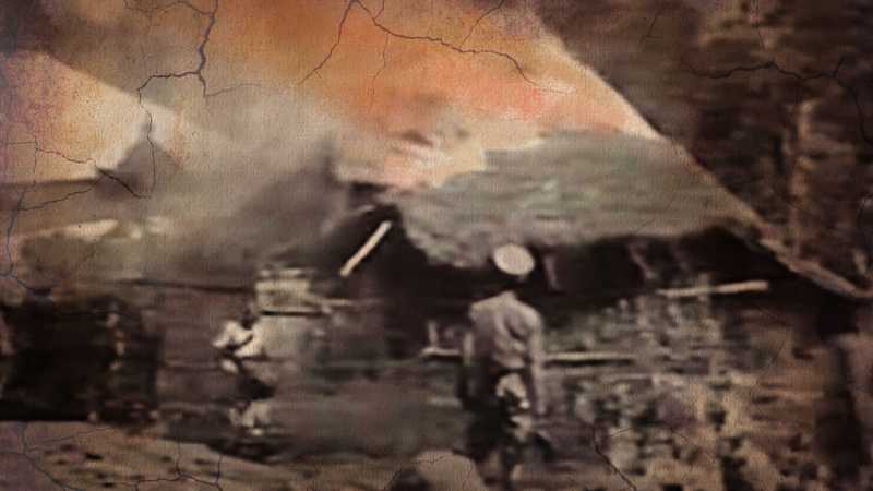 An Ethiopian soldier looks on as a village burns